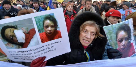 A protestor holds photos of journalist Tetyana Chornovil outside the Internal Affairs Ministry in Kiev.