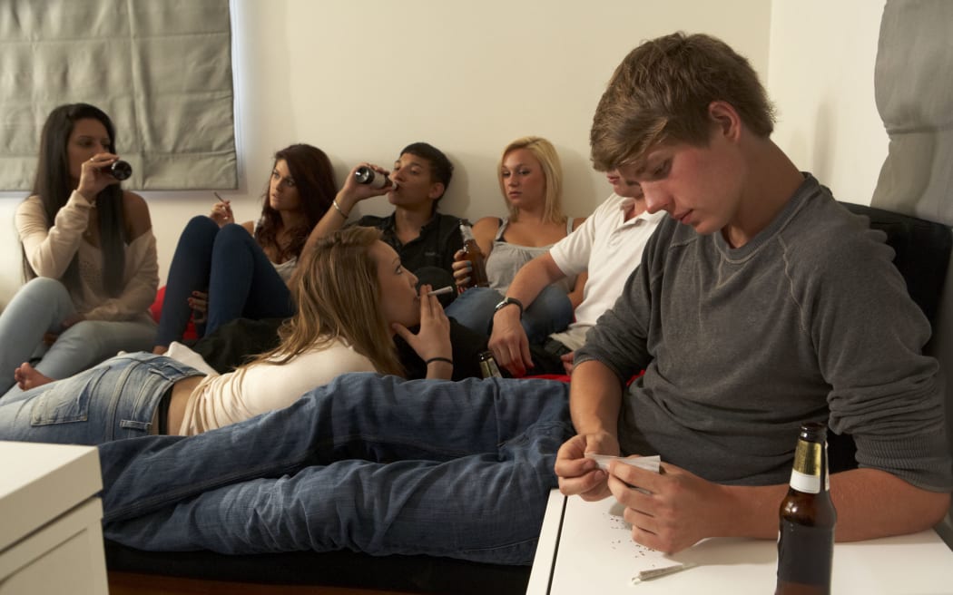 A photo of teenagers drinking and smoking in a bedroom togther