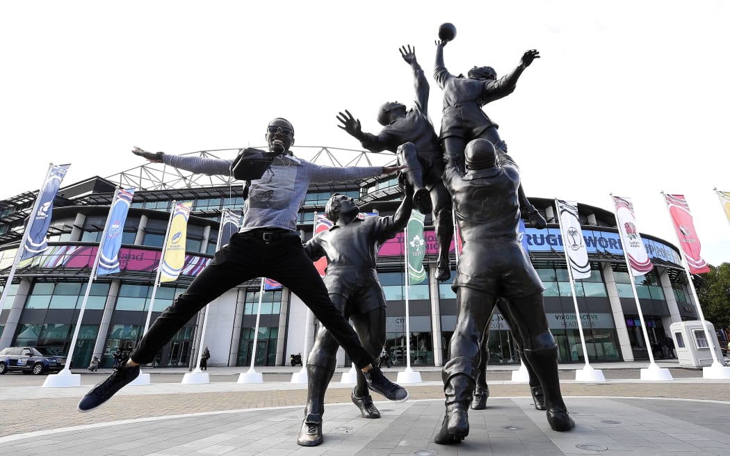 A man jumps next to a statue outside Twickenham Stadium on the eve of the Rugby Union World Cup opening match.