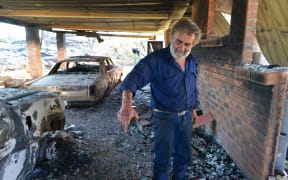 Resident David Miller pours the remains from a wine bottle that melted in the intensity of the heat when his home near Kersbrook was destroyed by a bushfire in the Adelaide Hills.