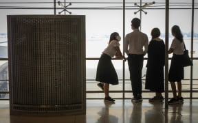 Students wearing protective face masks stand overlooking the runway in a viewing deck at Suvarnabhumi Airport in Bangkok on February 21, 2020.