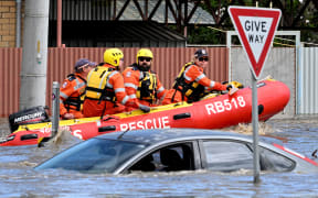 Emergency workers look at a submerged car on a flooded street in the Maribyrnong suburb of Melbourne on October 14 October, 2022.