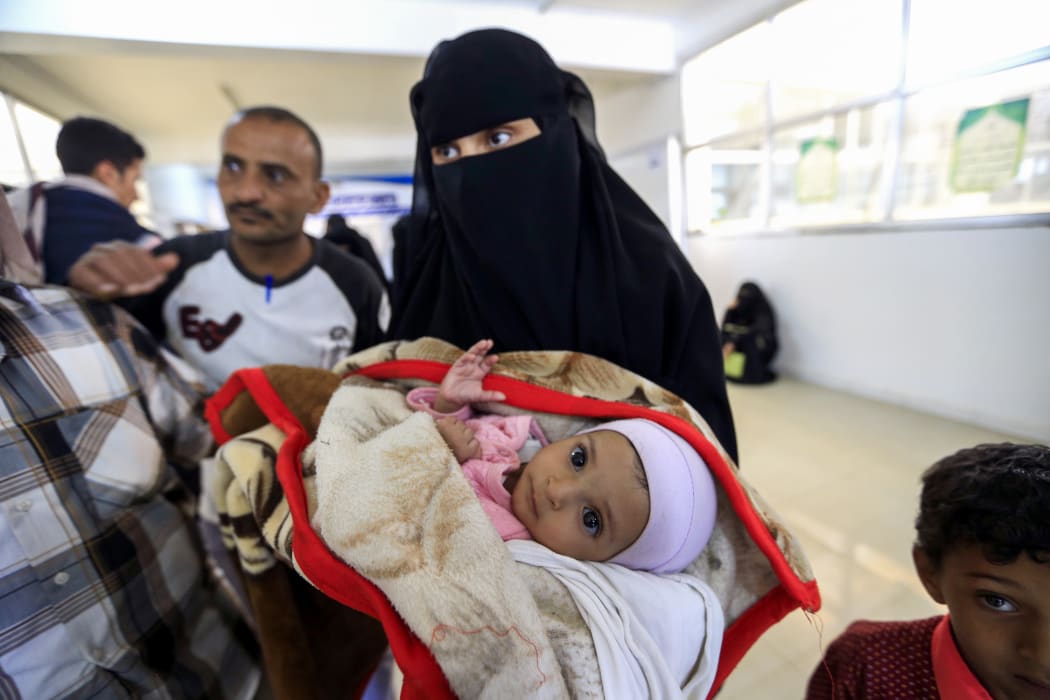 A Yemeni woman carries an ill child.