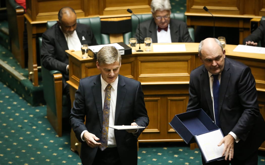 Bill English (left) and Steven Joyce handing out the Budget to parliament members in the house.
