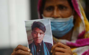 A mother, Jamena, shows a photo of her missing son Naim, 17, at Dhaka Medical College Hospital, she fears he died in the Hashem Foods fire in the outskirts of Dhaka.