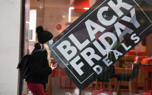 A pedestrian wearing a mask because of the novel coronavirus pandemic walks past a shop advertising Black Friday sales on Oxford Street in London on November 26, 2020.