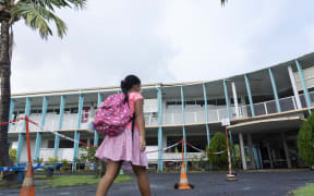 Schoolchildren wearing protective face masks arrive at the Taimoana Primary school in Papeete