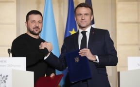 France's President Emmanuel Macron (R) shakes hands with Ukraine's President Volodymyr Zelensky (L) at the presidential Elysee palace in Paris on 16 February, 2024, after signing a bilateral security agreement.