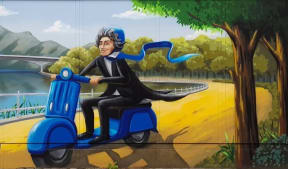 A caricature of Beethoven driving a blue motor scooter (and wearing a matching helmet) along a path next to a river.