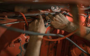 A worker fixing a machine with tools.