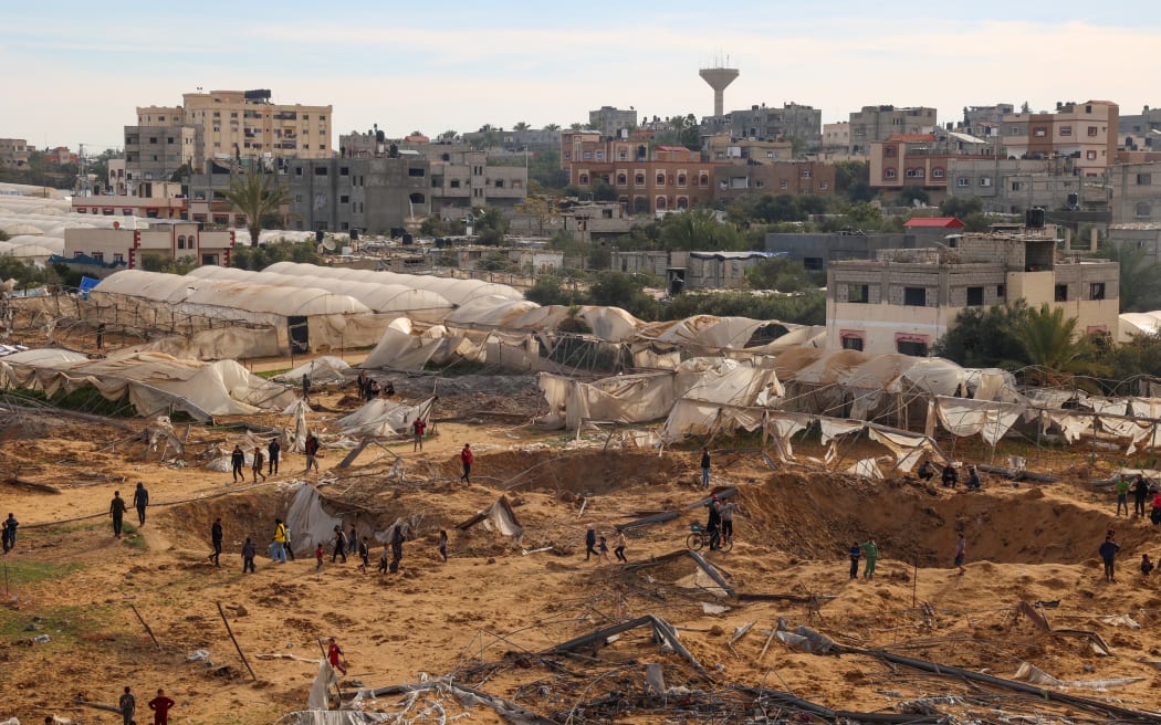 People stand around craters caused by Israeli bombardment in Rafah on the southern Gaza Strip on February 12, 2024.
