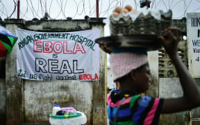 A girl walks past a sign warning of the dangers of Ebola outside a government hospital in Freetown, Sierra Leone, in August 2014.