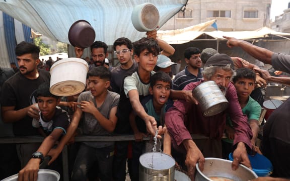 Palestinian children queue for a portion of hot food distributed by a charity kitchen at the Nuseirat refugee camp in the central Gaza Strip on July 15.