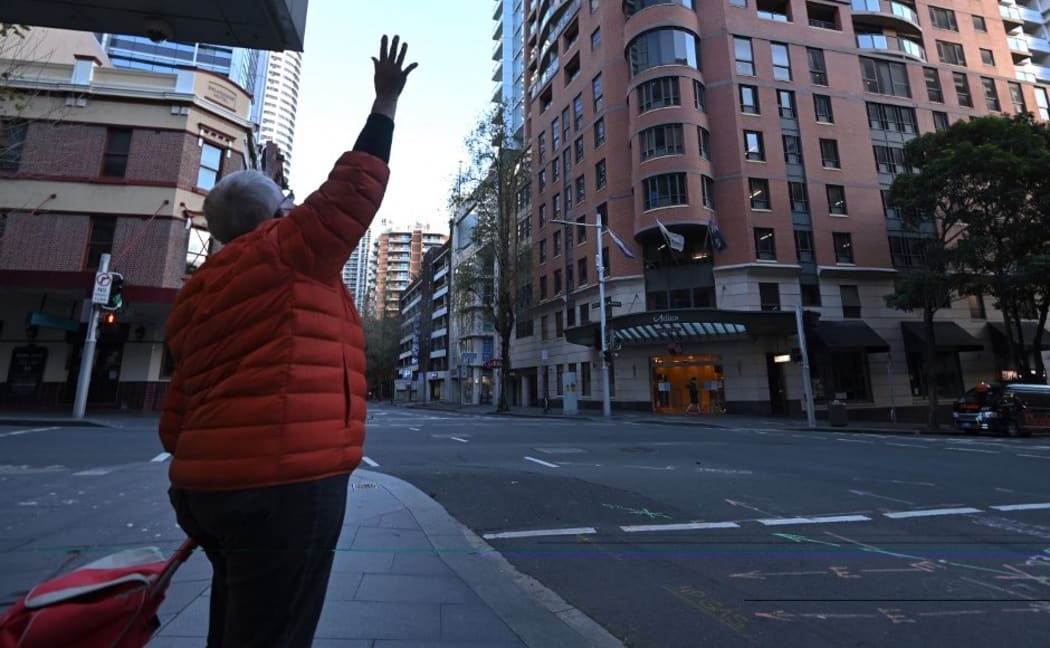 A woman waves to her family members in quarantine at a hotel in Sydney on July 17, 2021, after authorities ordered new restrictions as a weeks-long lockdown failed to quash an outbreak of the Covid-19 coronavirus.