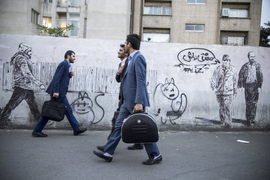 Iranians walk past mural in Tehran on May 8.