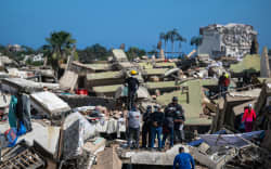 Volunteers and residents search for survivors on the rubble of collapsed buildings in Caraballeda, La Guaira state, Venezuela, on June 28, 2026, following earthquakes. Thousands of rescuers, relatives and volunteers dig day and night through mounds of concrete to find survivors of the earthquakes that struck Venezuela more than three days ago, leaving nearly 1,500 dead and tens of thousands missing. (Photo by Miguel MEDINA / POOL / AFP)