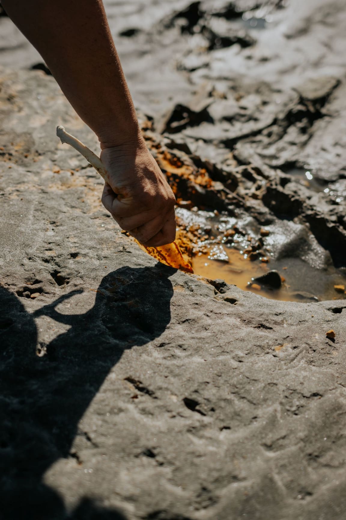 Scraping orange clay with Kauae Raro