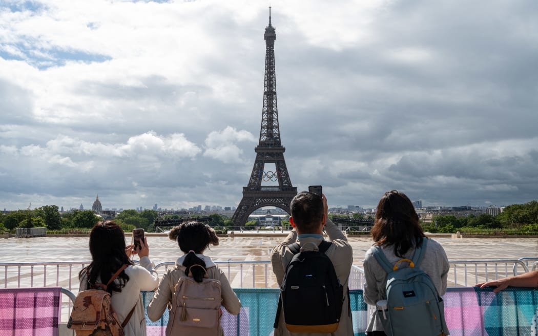 Tourists taking photo. Illustration of the Olympic rings (anneaux olympiques) displayed on the Eiffel Tower seen from the Trocadero in the 16th arrondissement of Paris, France, on July 16, 2024. For the Olympic Games Paris 2024 Olympic Games, the symbol of the Games, the five Olympic rings are hung on the Eiffel Tower, the symbol of Paris. (Photo by Riccardo Milani / Hans Lucas / Hans Lucas via AFP)