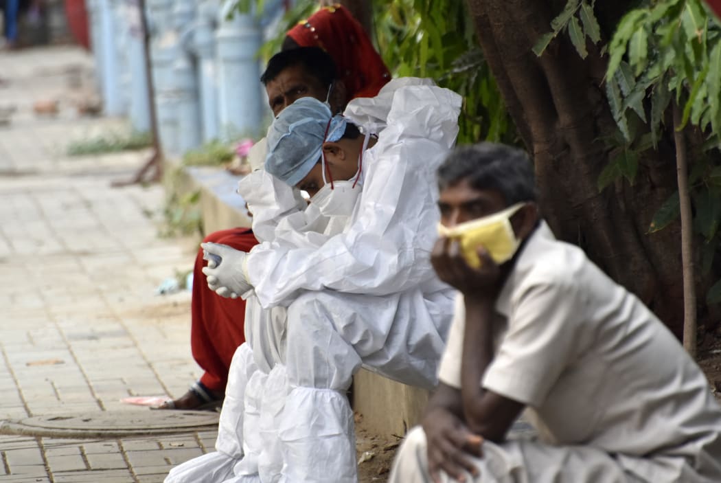A health worker wearing a PPE Kit, rests on a foothpath of a government hospital during coronavirus emergency in Kolkata, India.