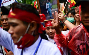 Protesters show the three finger salute and hold photos of detained Myanmar civilian leader Aung San Suu Kyi during a demonstration against the Myanmar military junta’s execution of four prisoners, outside the Myanmar Embassy in Bangkok on 26 July, 2022.