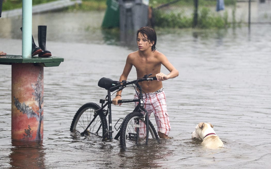 A young man and his dog wade in the storm surge from Hurricane Hermine outside Cooter Stew Cafe in Saint Marks, Florida.