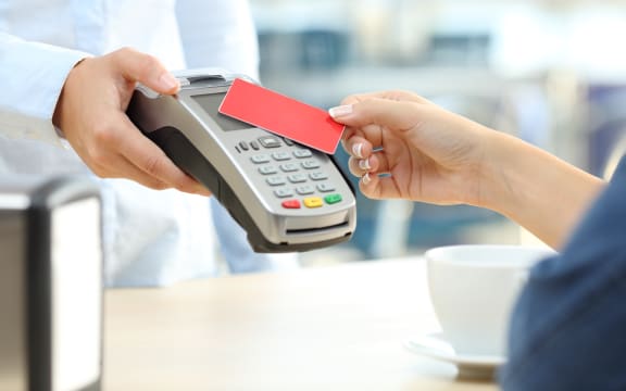 Close up of a customer hand paying with a contactless credit card reader in a bar