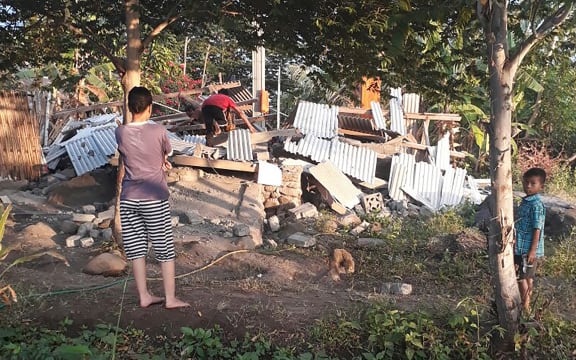 Indonesians scramble over the collapsed ruins of a house as others look on following an earthquake in Lombok.