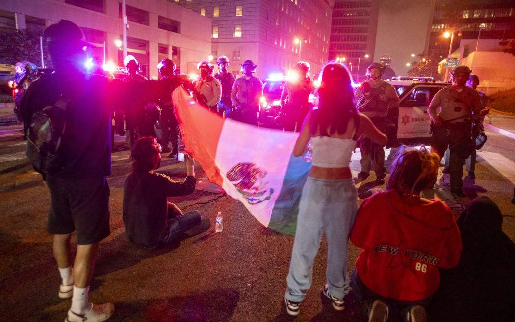 Protesters with a Mexican flag face off with Sheriff deputies during a protest following federal immigration operations in Los Angeles, California, on 8 June, 2025.