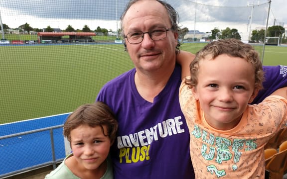 Man with two young children alongside football pitch