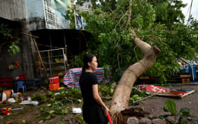 A woman clears debris outside an eatery next to uprooted trees in central Vietnam's Quang Ngai province in the aftermath of Typhoon Molave.
