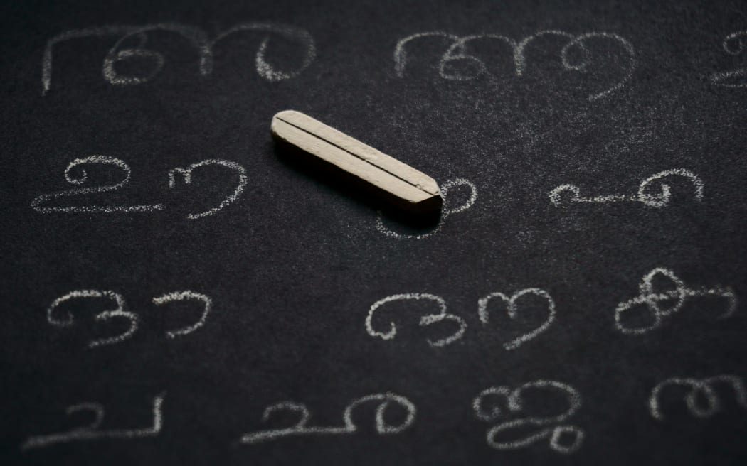 Selective focus of random Malayalam alphabets written on a kid's slate board isolated on white background.