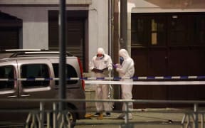 Belgian police officers from the forensic service search for evidence in a street after two people were killed during a shooting in Brussels on October 16, 2023 evening by a suspect who is on the run, the Belgian capital's prosecutor's office said. The alleged gunman in a fluorescent orange jacket fled the scene after using an automatic rifle, according to a video shared by Flemish newspaper Het Laatste Nieuws. A spokeswoman for the prosecutor's office said an investigation had been opened but did not speculate on the gunman's motive. (Photo by Kenzo TRIBOUILLARD / AFP)