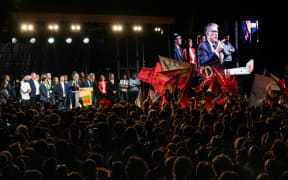 First Secretary of the French left-wing Socialist Party (PS) Olivier Faure addresses a speech on stage and is shown on screen (R) at a rally following the announcement of the results of the first round of French parliamentary elections, at Place de la Republique in Paris on June 30, 2024.