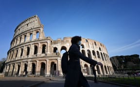 A tourist wearing a respiratory mask as part of precautionary measures against the spread of the new COVID-19 coronavirus, walks past the closed Colisseum monument in Rome.