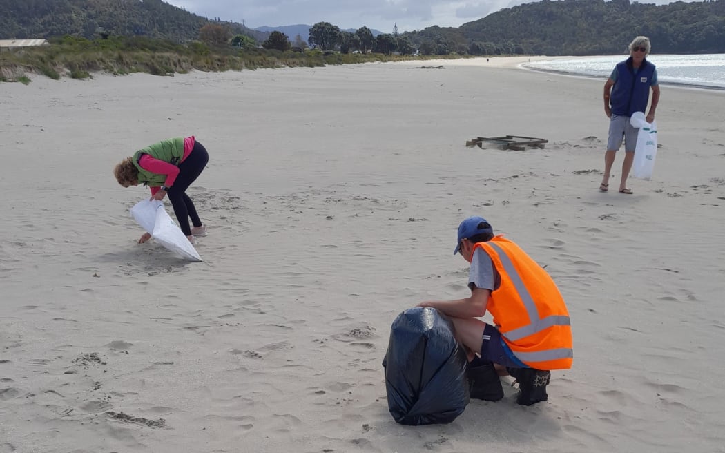 Contractors for Thames Coromandel District Council and local residents check Cooks Beach for rubbish and debris from the sunken boat.