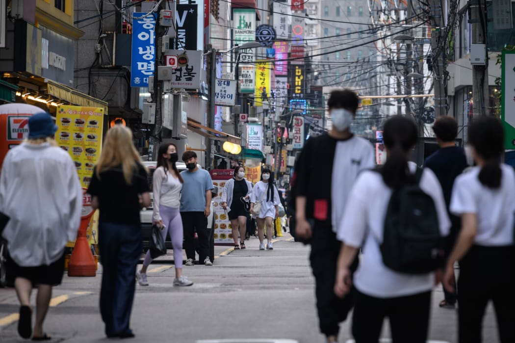 Pedestrians wearing face masks walk on a street in Seoul on August 24, 2020
