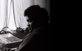 A black-and-white image of Chris Faiumu, co-creator of Fat Freddy's Drop, working at some recording equipment in the early 2000s.