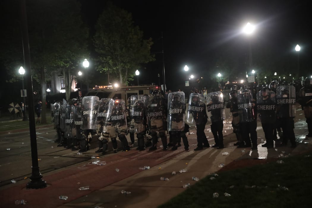 Police officers stand guard in front of the Kenosha County Courthouse during a second night of rioting in Wisconsin.