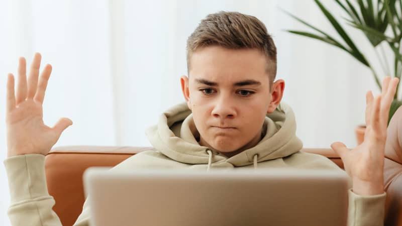 young boy looks angrily at his laptop
