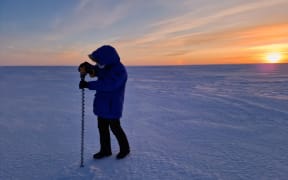 A member of the Real Ice team takes measurements on the sea ice in Cambridge Bay in January 2024.