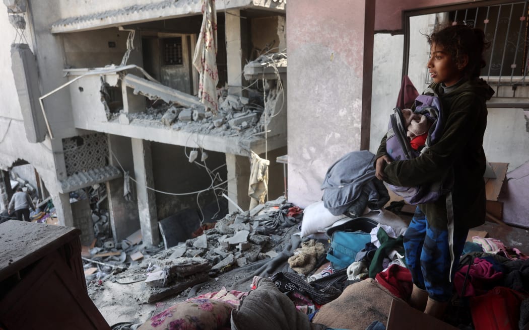 A Palestinian girl salvages items from a damaged house near the Qrayqea family house that was destroyed in Israeli strikes at dawn in the Shujaiya district in eastern Gaza City on March 18, 2025. Israel on March 18 unleashed its most intense strikes on the Gaza Strip since a January ceasefire, with Gaza's health ministry saying their toll rose to 413 people killed, and the Palestinian Hamas movement accusing Israel's premier of deciding to "resume war" after a deadlock on extending the truce. (Photo by Omar AL-QATTAA / AFP)