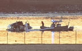 Part of the wreckage is seen as rescue boats search the waters of the Potomac River after a plane on approach to Reagan National Airport crashed into the river outside Washington, DC, on January 30, 2025. A regional jet from Kansas crashed into Washington's Potomac River after colliding mid-air with a military helicopter near Reagan National Airport, officials said January 29, prompting a major emergency response and grounding all flights. (Photo by ANDREW CABALLERO-REYNOLDS / AFP)