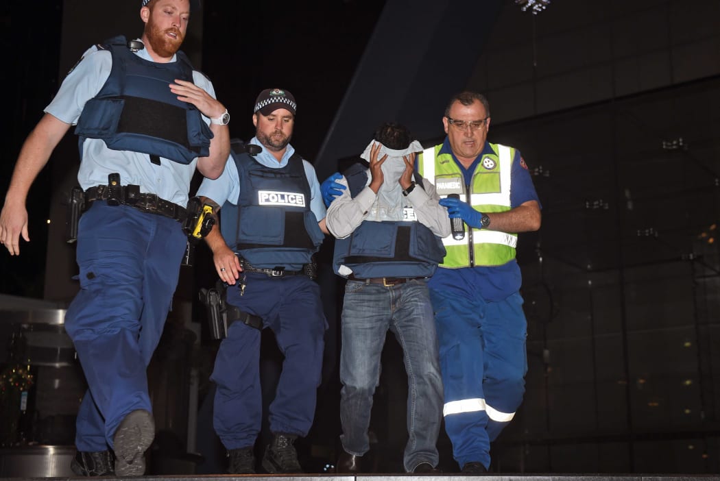 Police escort a hostage to safety with the help of a paramedic.