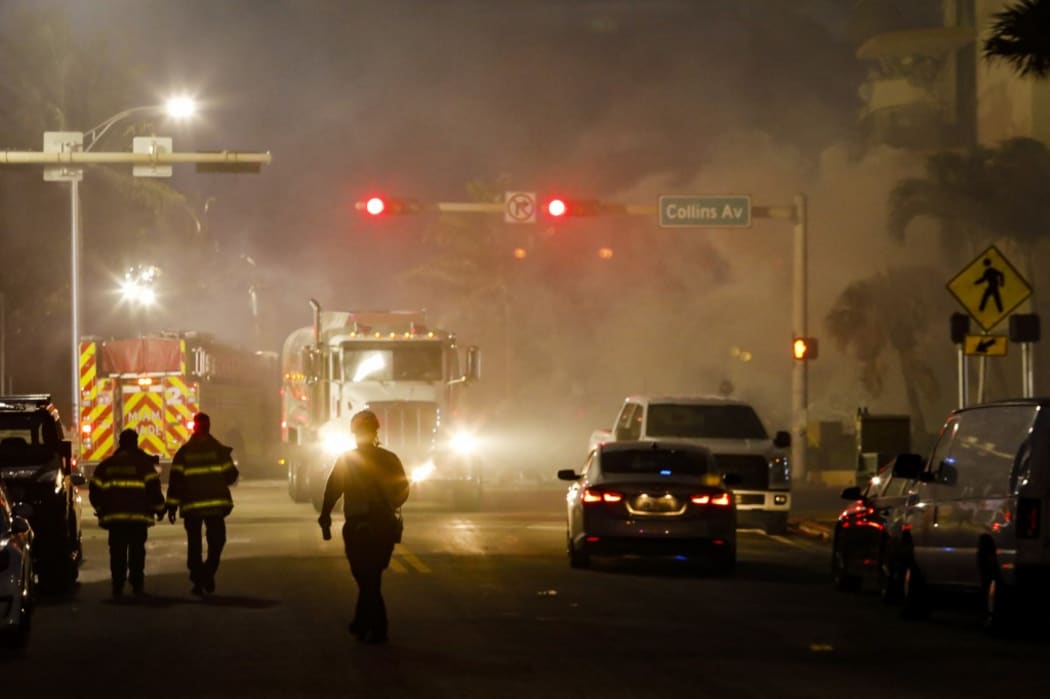 Miami-Dade firefighter walk next to a partially collapsed building in Surfside north of Miami Beach, Florida on June 25, 2021.