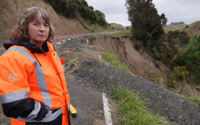 Tararua mayor Tracey Collis stands in front of one of the many slips on River Road, now the only way to coastal community Ākitio.