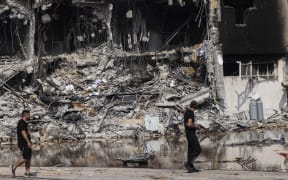 People walk past an Israeli police station in Sderot after it was damaged during battles to dislodge Hamas militants who were stationed inside, on October 8, 2023.