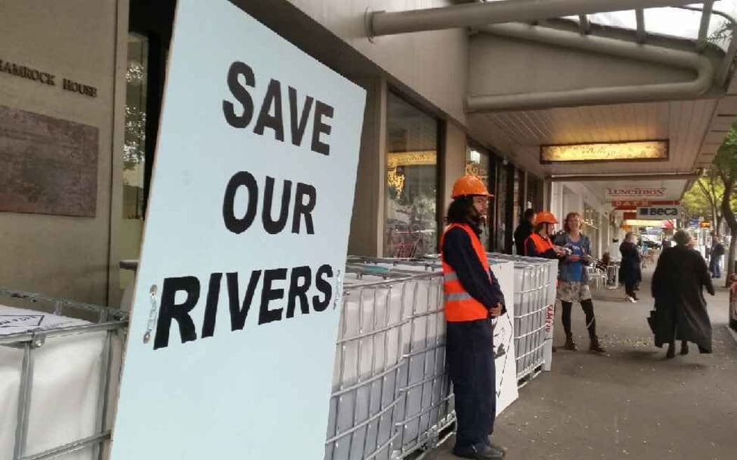 Greenpeace protesters stand in front of tanks of dairy waste in Wellington.