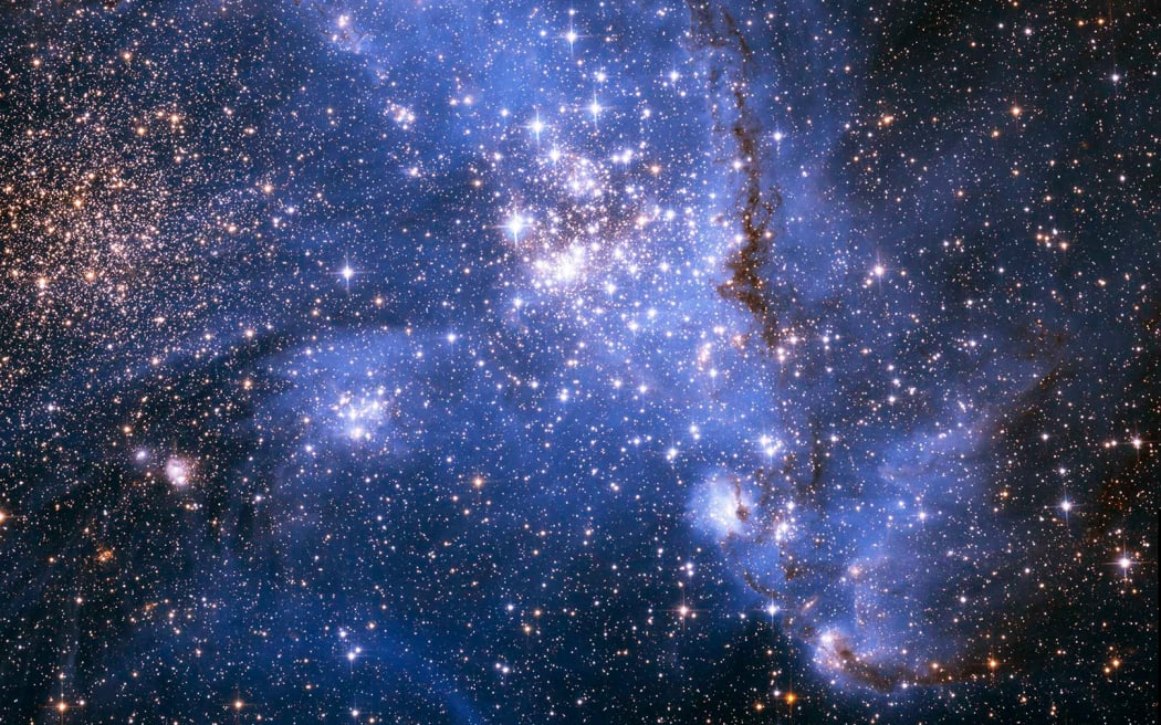 This handout image released on September 8, 2022, by NASA - ESA, captured by the Hubble Telescope, shows young stars spiralling into the centre of a massive cluster of stars in the Small Magellanic Cloud, a satellite galaxy of the Milky Way. - The outer arm of the spiral in this huge, oddly shaped stellar nursery — called NGC 346 — may be feeding star formation in a river-like motion of gas and stars. This is an efficient way to fuel star birth, researchers say. (Photo by NASA/ESA / AFP) / RESTRICTED TO EDITORIAL USE - MANDATORY CREDIT "AFP PHOTO / NASA - ESA" - NO MARKETING NO ADVERTISING CAMPAIGNS - DISTRIBUTED AS A SERVICE TO CLIENTS