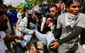 Demonstrators carry an injured victim during a protest outside the Parliament in Kathmandu on September 8, 2025, held to condemn the government over social media prohibitions and corruption. At least 16 protesters were killed on September 8 after Nepal police fired rubber bullets, tear gas and water cannon to disperse demonstrators demanding the government lift its ban on social media and tackle corruption. (Photo by Prabin RANABHAT / AFP)