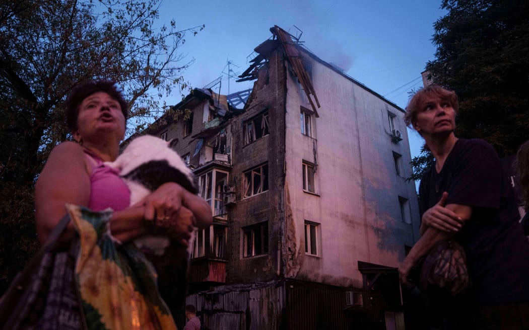 Residents stand outside of their damaged house in Kyiv, following a Russian strike.